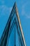 Facade of modern office building with glass and steel under blue sky, reflections and selective focus.