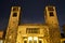 The facade of a modernist church with two bell towers at night