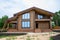 Facade of new house under construction, unfinished wooden home painted with brown natural color.