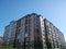 Facade of new multi-story residential building. Blue sky background. House Share. Real estate investing. Buy, sale, rental and ins