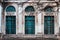 Facade of old abandoned building with large arched windows and columns