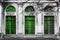 Facade of old abandoned building with three large arched windows of green glass. Monochrome background