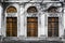 Facade of old abandoned building with three large arched windows of orange glass. Monochrome background