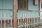 Facade of old abandoned house with rusty metal fence and grungy weathered green wood wall