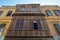 Facade of an old residential building with wooden ornate engraved wall, yellow painted wall, and violet painted wooden windows