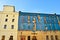 The facade of an old ruinous building is mantled with some blue curtains to protect the pedestrians