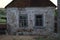 Facade of an old rural house with two windows. Abandoned building