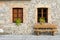 Facade of an old stone building recently renovated. Two closed windows and a wooden bench.