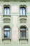 The facade of an old stone building. Windows and decorative stucco figures