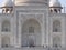 Facade with one of the entrances of the white marble mausoleum with four minarets and large domes. Taj Mahal