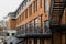 Facade of red brick building with outdoor iron stairs. Industrial building converted into offices and retail space