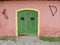 Facade of red farmhouse with rusty tools hanging on wall in Italian countryside.