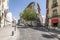 Facade of residential buildings with young trees at a crossroads with stone cobblestone floors in the center of Madrid, Spain