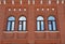 Facade of a restored city building made of red brick with arched windows. Element of architecture