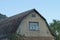 Facade of a rural house with a brown brick attic with a large window under a gray slate roof