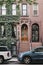 Facade of a typical New York house with a stoop, cars park outside.