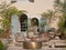 Facade of a vintage house full of vegetation with garden tables and wicker chairs