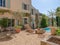 Facade of a vintage house with a pool, garden tables and gravel on the ground