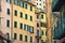 Facade of yellow and pink houses of Riomaggiore with green windows with wooden shutters and balconies , Cinque Terre