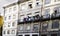 Facades of old houses in the center of the city with clothes hanging to dry, including a flag of Portugal, on the iron balconies i