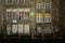 Facades of old houses with lots of windows and walkway along river Lys in Ghent at night