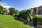 Facades of semi-detached single-family residential homes in an urbanization with common areas full of grass and leafy trees