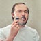 Face adult man close-up who shaves his beard with a safety razor, lifestyle