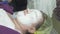 Face of adult thick woman lie in beauty saloon with anti age algae mask.