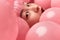 Face of amazed Asian woman in pink balloons