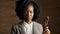Face, art and violin with black woman performer in studio on wooden wall background for orchestra music. Portrait