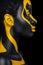 Face art. Woman with black and yellow body paint. Young african girl with colorful bodypaint. An amazing model with