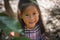 The face of asian little girl surrounded by tropical leaves. Closeup portrait of a beautiful swarthy baby with tan skin and dark