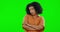 Face, attitude and a woman on a green screen with arms crossed and curly afro hair. Young female model on a studio