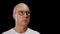 Face bald man in glasses, white t-shirt on black background. Portrait serious man in glasses looking front, isolated