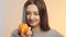 Face of a beautiful girl with fruit orange on a studio background, happy young woman enjoys the fruit and advertises it, the conce