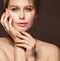 Face Beauty Woman. Model with Full Plump Glossy Lips and Smooth Skin holding Hands with Nude Nail Polish on Cheek over Dark