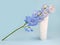 Face and body cream squeeze cosmetic tube with moisturizer and blue Delphinium flower on blue background. Natural organic