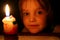 the face of a charming small girl lit by candlelight