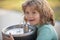 Face close up portrait of kid drinking water from outdoor water fountain outdoor.