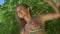 Face closeup of pretty blonde woman in bikini sitting on a branch