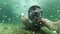 The face of a diver diving in a mask with a snorkel under the water. Slow-motion underwater selfie among air bubbles.