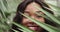 The face of a girl with clean skin with natural makeup among exotic plants, a young African American woman. Advertising