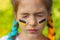 The face of a girl with closed eyes and with yellow-blue national flags of Ukraine painted on her cheeks