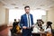 Face of handsome arabian business man, holding clipboard on the background of business peoples multiracial team meeting, sitting