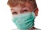 Face of a handsome white old boy in a green protective surgical mask. Tricky gray eyes.The child grimaces under a mask, squints