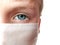 Face of a handsome white seven year old boy in a white protective surgical mask. Eye with a light gray iris. Half face. Blonde