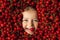 The face of a happy, cheerful child surrounded by a large number of cherries