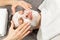 Face of laying man with cream mask and hands of beautician