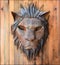 face of a lion made of metal on a wooden canvas