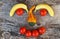A face made of bananas, tomatoes and a pumpkin on a wooden background